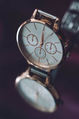 Siyah ayna arkaplanındaki altın renkli lüks kol saatini kapat.