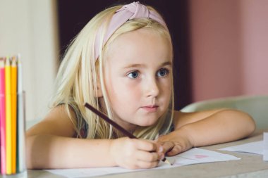 Renkli kalemlerle çizen tatlı bir kız. Evde eğitim ve eğitim kavramı.