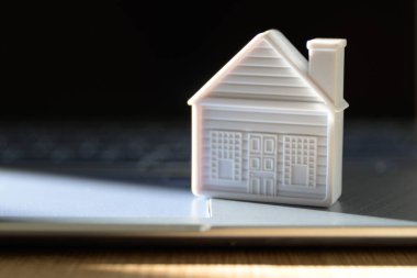 Dizüstü bilgisayarda küçük bir ev. Emlak ajansı online konsepti