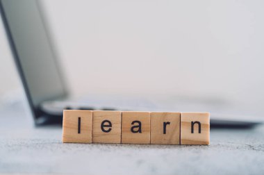 Çevrimiçi eğitim kavramı. Tahta bloklar ve parlak arka planda izole edilmiş dizüstü bilgisayar hakkında bilgi. Öğrenim, eğitim ve bilgi, öğrenim kavramı