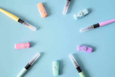 Açık mavi arkaplanda izole edilmiş renkli fosforlu kalemler.