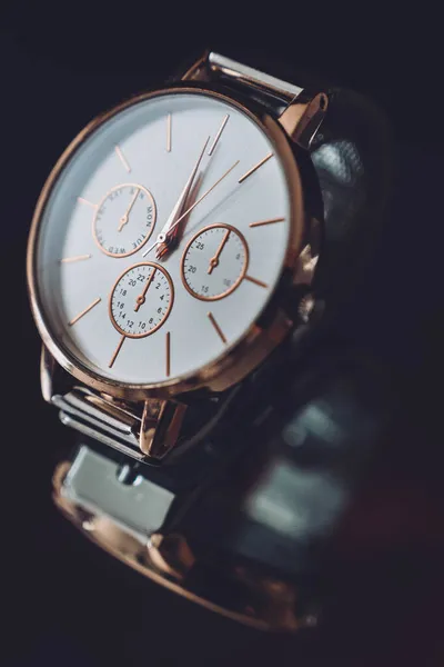 Close up of golden elegant luxury watch wristwatch on black mirror background