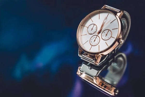 Close up of golden elegant luxury watch wristwatch on black mirror background