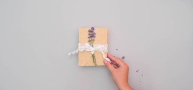 Yay ve lavantalarla süslenmiş, gri arka planda fotokopi alanı ile süslenmiş, hediye tutan kadınların düz uzantısı