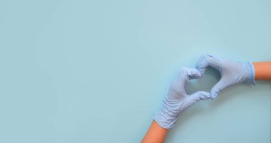 Doktorun elleri mavi arka planda kalp şeklinde tıbbi eldivenlerle. Kopya alanı olan web sitesi için pankart.