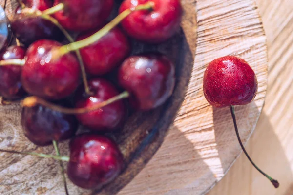 Tahta tepside kiraz manzarası. Ahşap arkaplanda organik kiraz meyveleri