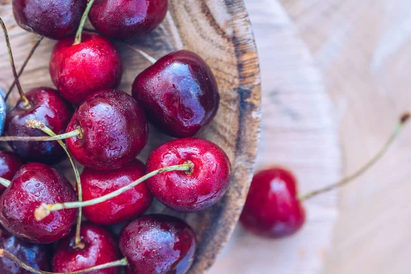 Tahta tepside kiraz manzarası. Ahşap arkaplanda organik kiraz meyveleri
