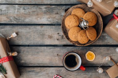 Noel tebrik kartı tasarımı. Bir sürü Noel hediyesi, çelenk, dekorasyon ve kırsal ahşap masada bir fincan kahve. Üst görünüm.