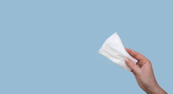 Рука держит салфетки или туалетную бумагу изолированы на синем фоне.