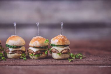Ahşap arka planda izole edilmiş mini sığır etli burgerlere yakın çekim