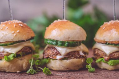 Ahşap arka planda izole edilmiş mini sığır etli burgerlere yakın çekim