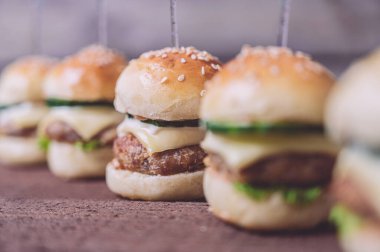 Ahşap arka planda izole edilmiş mini sığır etli burgerlere yakın çekim