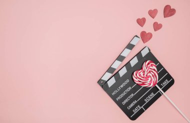 Sevgililer Günün kutlu olsun. Pembe zemin üzerinde kırmızı kalpler olan bir alkış tahtası. Romantik film konsepti