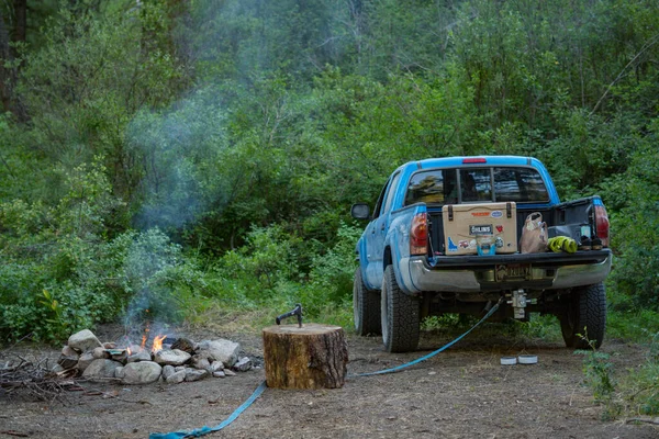 Toyota Tacoma at a campsite with a fire and a log