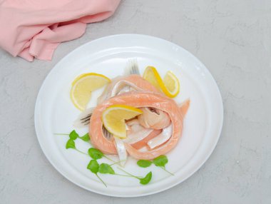 Arka planda beyaz bir tabakta limonlu tuzlu somon göbeği parçaları. Deniz mahsulleri..