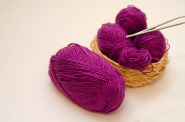 Beyaz arka planda renkli örgü iplikleri ve örgü iğneleri. İğne işi ve stres atımı