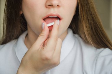 Kız ağzına beyaz hap koyuyor. tıp konsepti