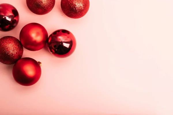 Kırmızı Noel toplarıyla çerçevelenmiş pembe arkaplan