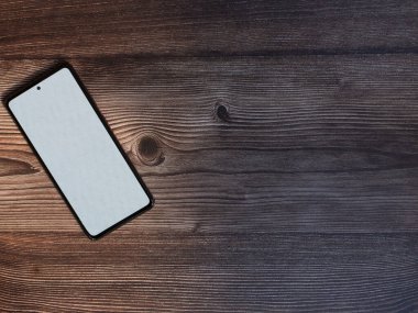 Koyu ahşap beyaz ekranlı düz bir cep telefonu yatağı.