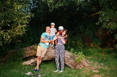 Mutlu genç aile: anne, baba, iki çocuk doğada eğleniyor..