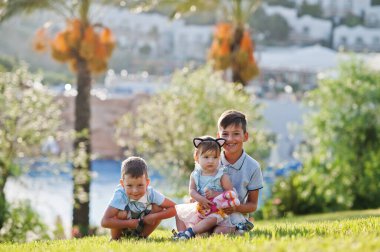 Türkiye 'de çimenlerde oturan üç çocuk palmiyelere yaslanıyor.