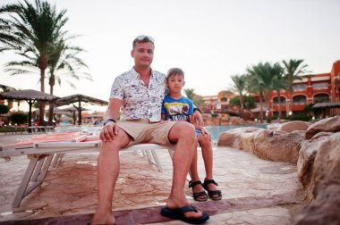 Baba oğul Mısır tatil köyü havuzunun yanında oturuyorlar.. 