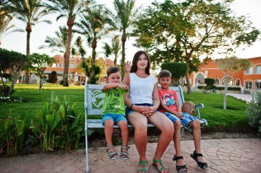 İki oğlu olan bir anne Mısır tatil köyünde bankta oturuyor. Aile tatili.