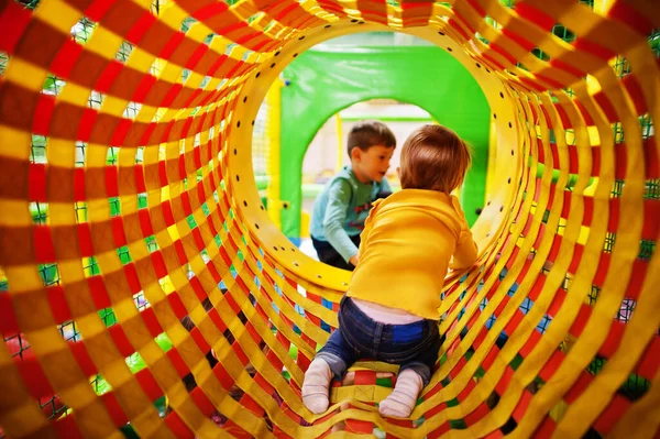 屋内プレイセンターで遊んでいる子供たち 幼稚園や幼稚園のプレイルーム 赤ちゃんの女の子はパイプに登る — ストック写真