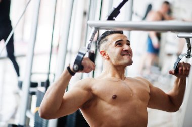 Modern spor salonunda kaslı Arap adam eğitimi. Vücutları çıplak, spor yapan Araplar. .