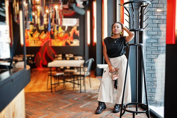 Kafede siyah bluzlu genç Afrikalı bir kadın var.. 