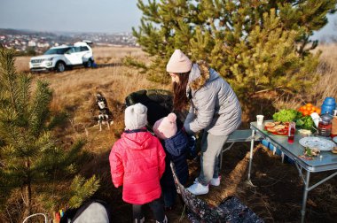 Anne kızlarıyla çam ormanında mangal yapıyor..