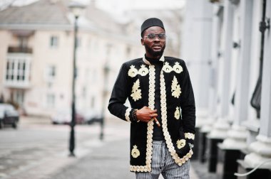 Geleneksel ceket giymiş mega stil Afrikalı bir adam. Şapkalı, güneş gözlüklü, elinde puro olan şık siyahi bir adam..