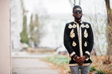 Geleneksel ceket giymiş mega stil Afrikalı bir adam. Şapkalı ve güneş gözlüklü şık siyah adam..