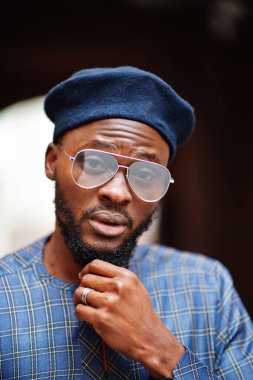 Mavi otantik kostümlü, gözlüklü ve bereli Afrikalı adam. Moda Nijeryalı Adam.