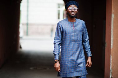 Mavi otantik kostümlü, gözlüklü ve bereli Afrikalı adam. Moda Nijeryalı Adam.
