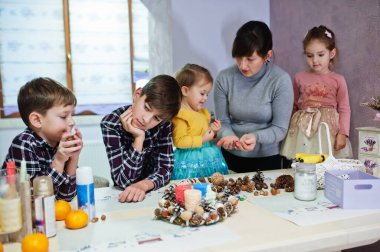 Dört çocuklu anne Noel arifesi için çelenk ve süsleme yapıyor. Yeni yıl kutlaması.