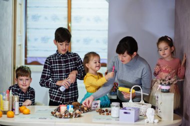 Dört çocuklu anne Noel arifesi için çelenk ve süsleme yapıyor. Yeni yıl kutlaması.