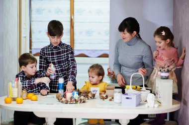 Dört çocuklu anne Noel arifesi için çelenk ve süsleme yapıyor. Yeni yıl kutlaması.