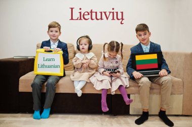 Dört çocuk yazıt gösterip Litvanyaca öğreniyor. Yabancı dil öğrenme kavramı.