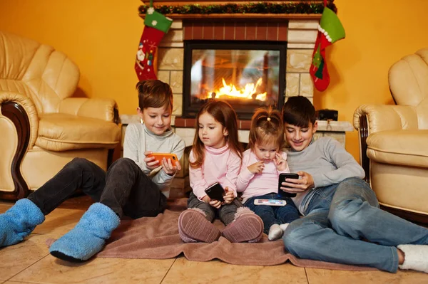 Щасливі Четверо Дітей Дивляться Мобільний Телефон Вдома Біля Каміна Теплій — стокове фото