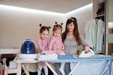 Kadın anne ve iki kızı, çocuk kızları evde ütü yapıyor..