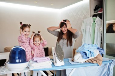 Kadın anne ve iki kızı, çocuk kızları evde ütü yapıyor..