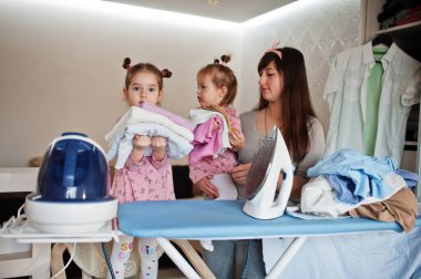 Kadın anne ve iki kızı, çocuk kızları evde ütü yapıyor..