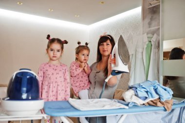 Kadın anne ve iki kızı, çocuk kızları evde ütü yapıyor..