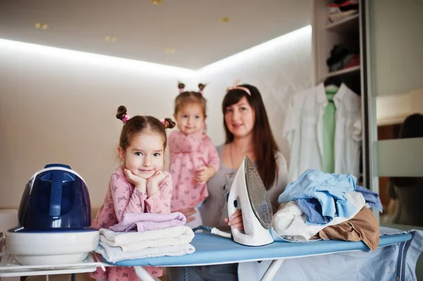 Kadın anne ve iki kızı, çocuk kızları evde ütü yapıyor..