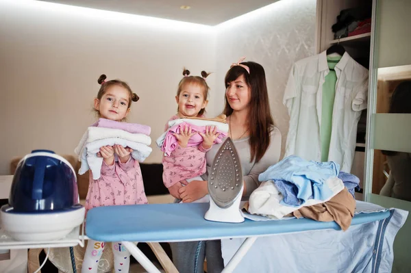 Kadın anne ve iki kızı, çocuk kızları evde ütü yapıyor..