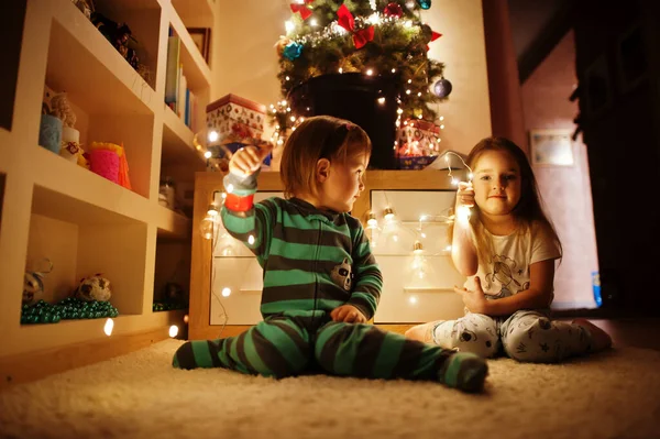 Two Baby Girl Sisters Looking Christmas Tree Shining Garlands Evening — Zdjęcie stockowe