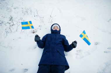 Scandinavian boy with Sweden flag in winter swedish landscape.