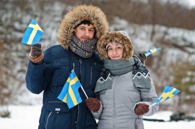 Scandinavian couple with Sweden flag in winter swedish landscape.
