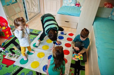 Mutlu bir aile birlikte eğleniyor, dört çocuk evde twister oynuyor..